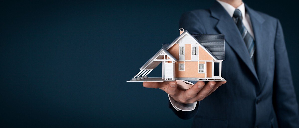 Mann mit Anzug hält Haus in der Hand Mann mit Anzug hält Haus in der Hand