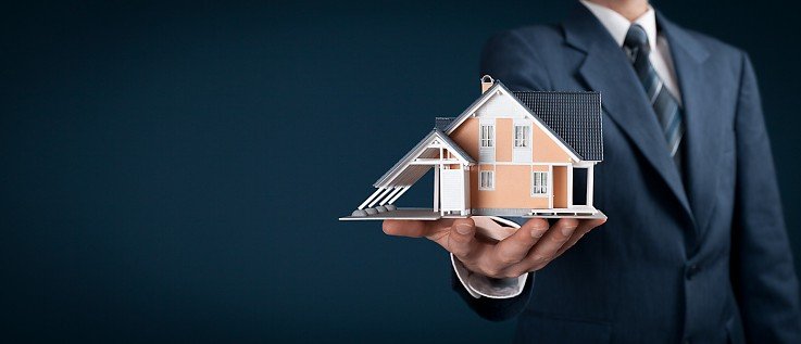 Mann mit Anzug hält Haus in der Hand Mann mit Anzug hält Haus in der Hand
